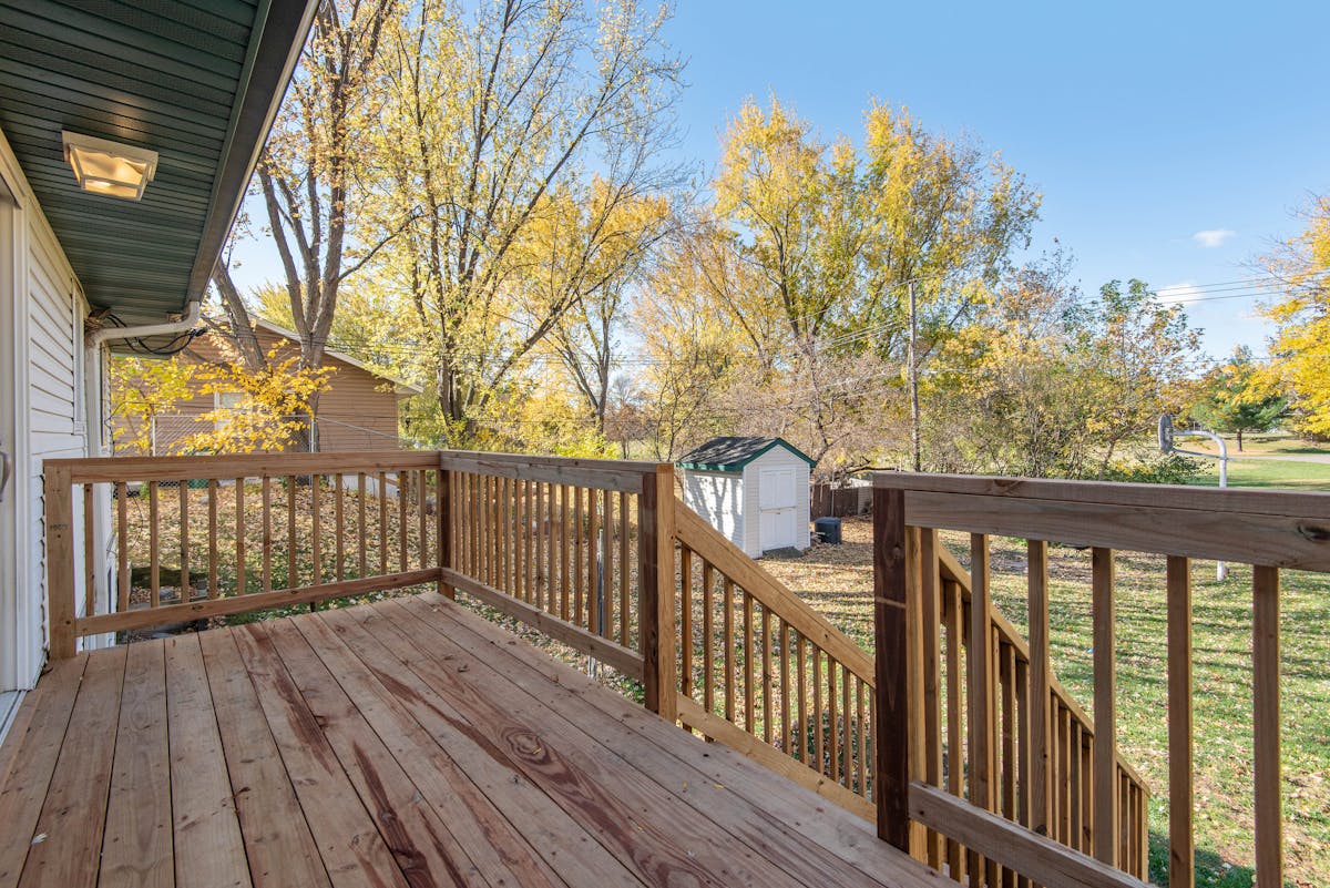 Wooden deck railing overlooking an autumn backyard showing a classic rail profile