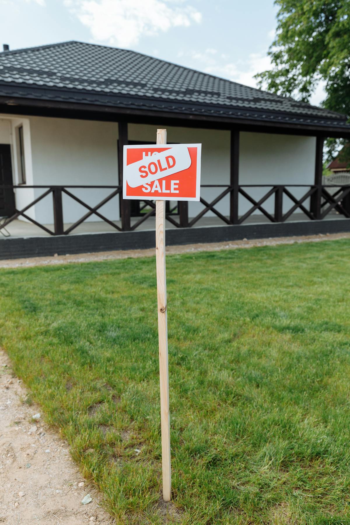 Modern house with a sold sign on the lawn representing deck resale return on investment