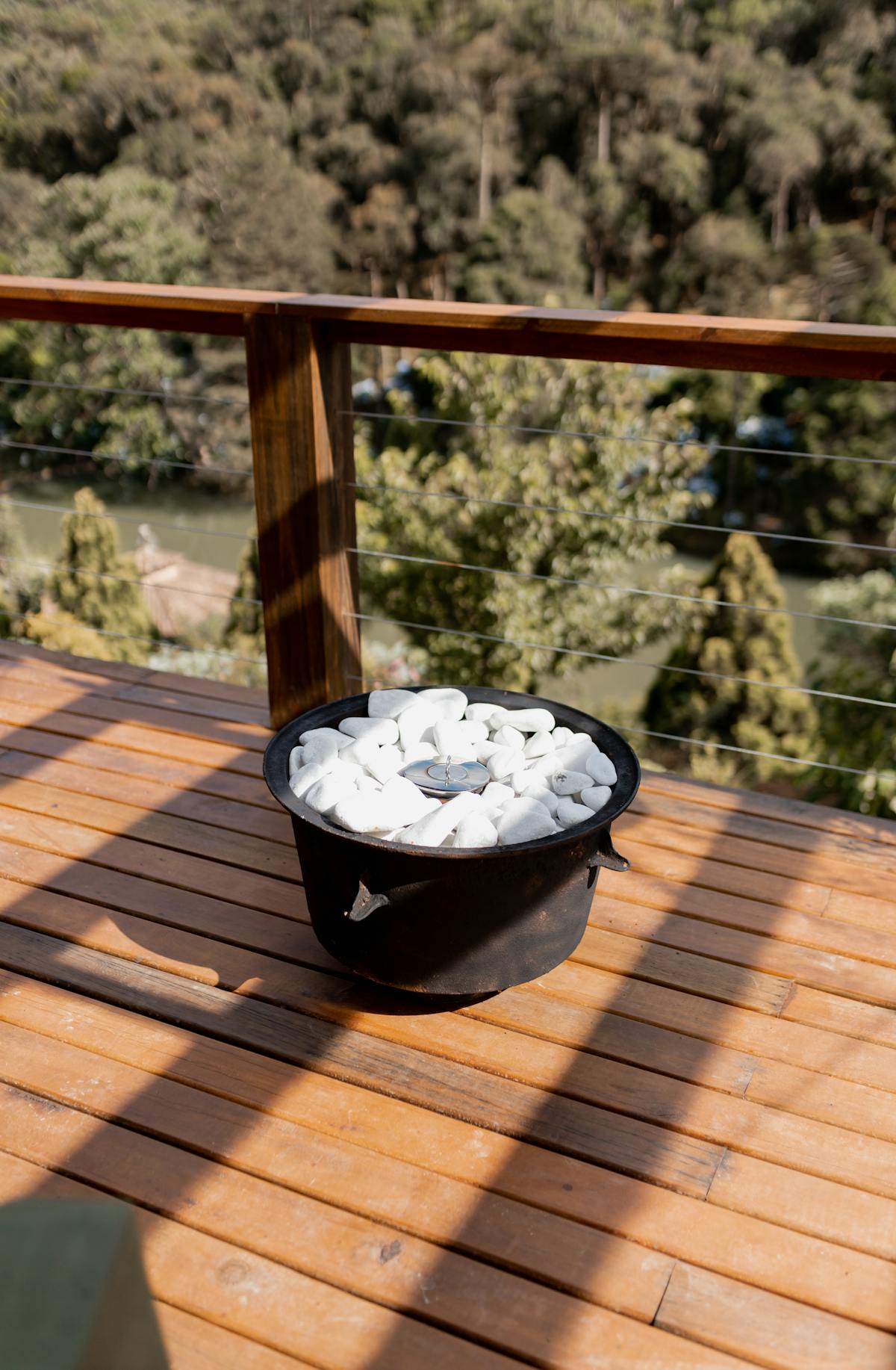 Modern composite deck with a round fire pit and white rocks on an outdoor balcony